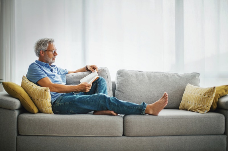 man reading a book on his couch