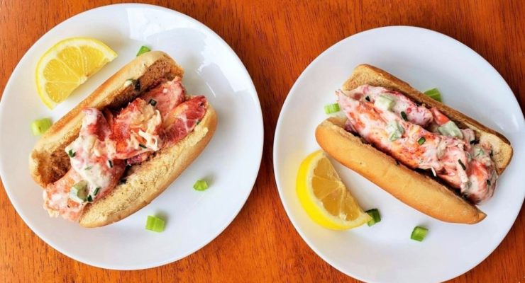 2 healthy Lobster Rolls on white plates with lemons and herbs