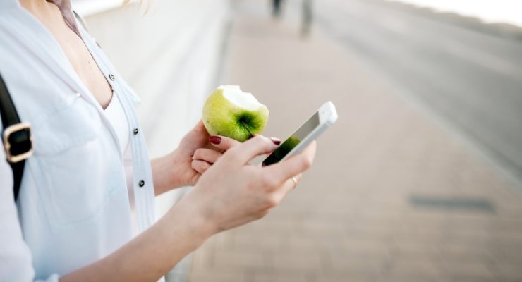 Using smartphone and eating apple