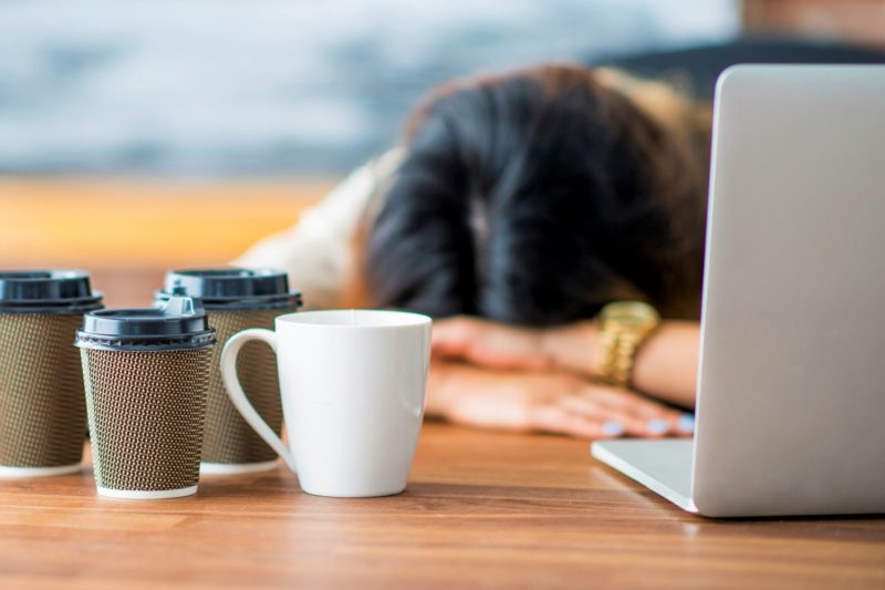 person sleeping while working with coffee cups