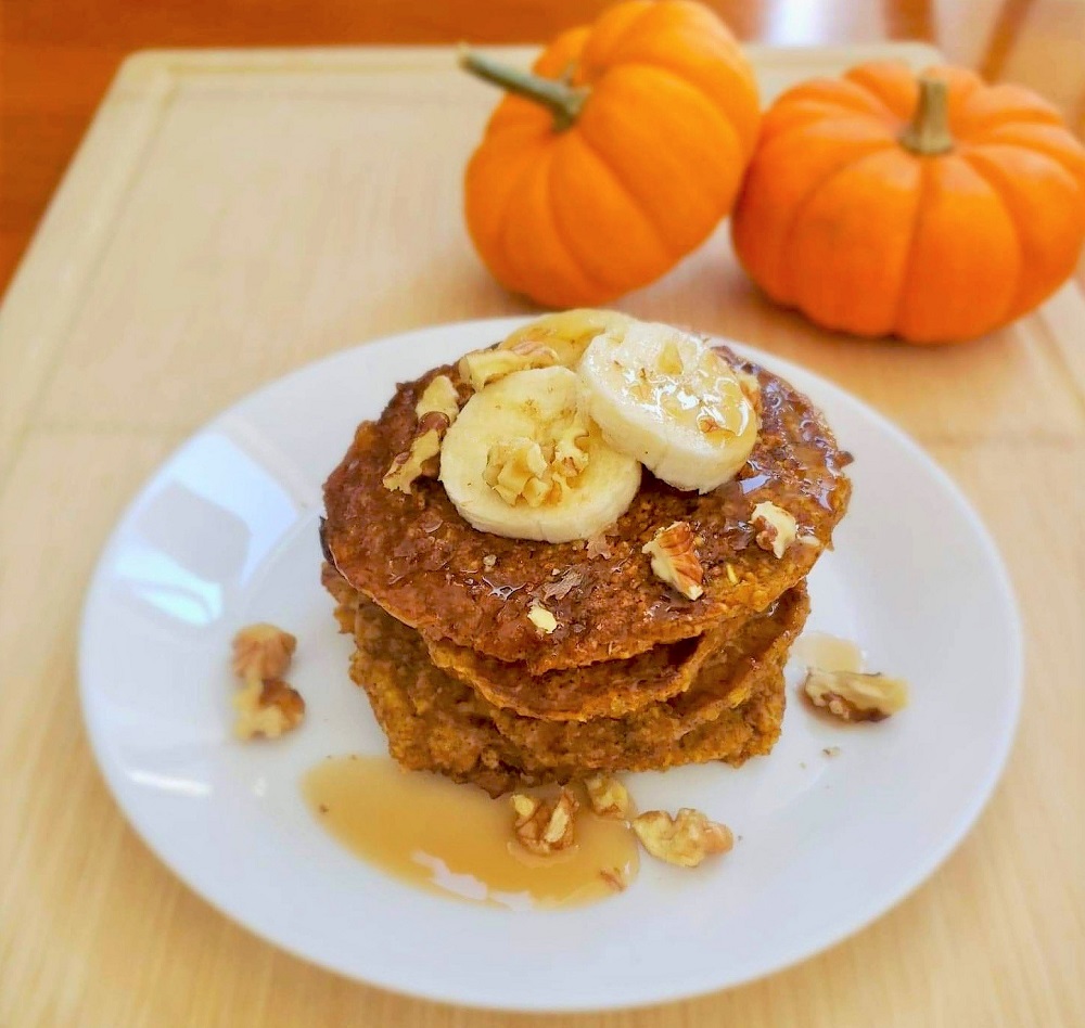 healthy pumpkin pancakes topped with bananas, walnuts and syrup