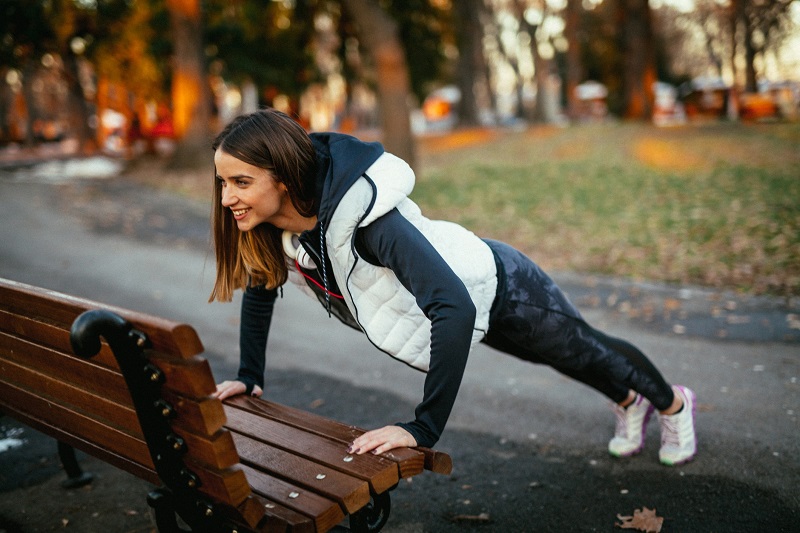 Woman doing a push up on a bench outside