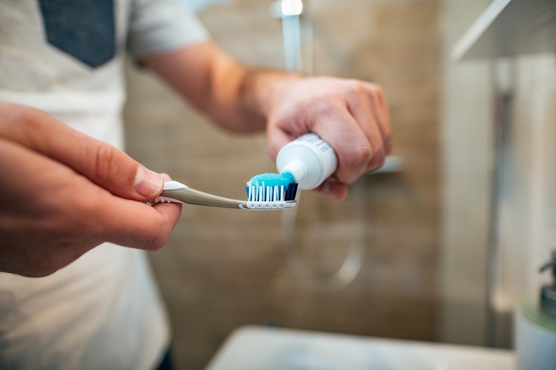 person putting toothpaste on a tooth brush