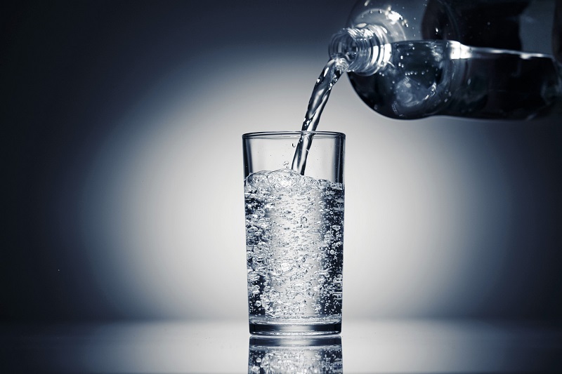 pouring sparkling water in a glass on a dark blue background