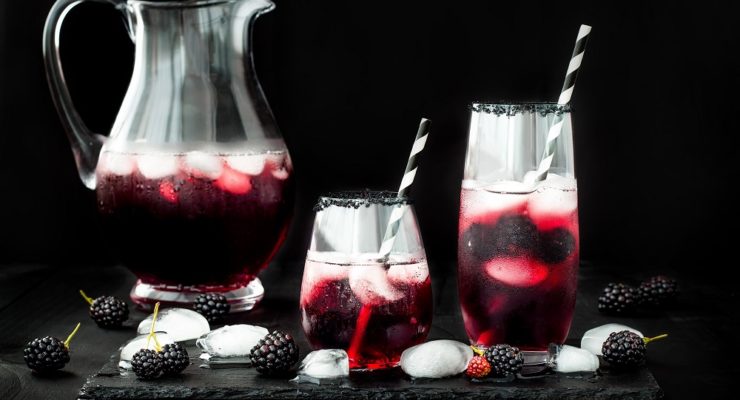 Halloween punch sangria with blackberries and ice cubes in a pitcher and glasses