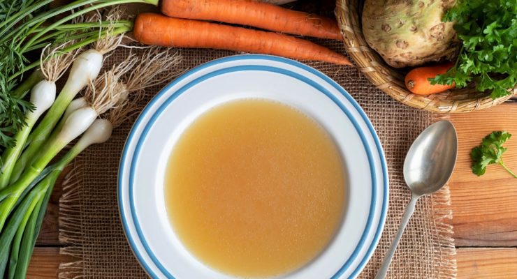 Chicken bone broth in a plate with vegetables