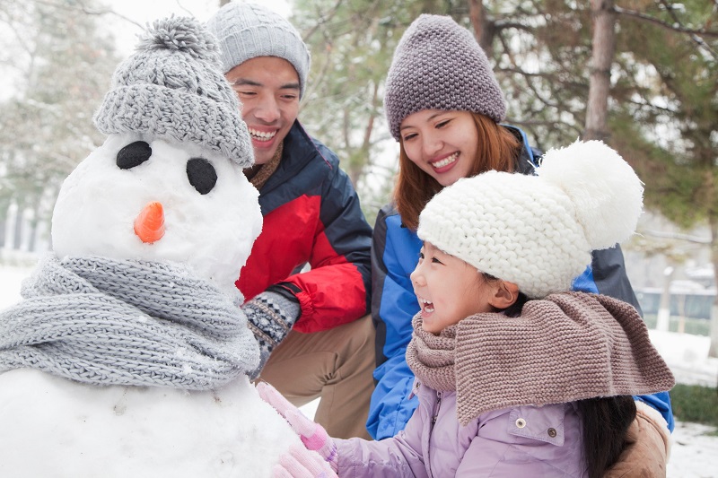 Family making snowman in winter