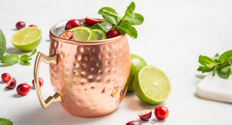 Cranberry Moscow Mule with mint leaves and lime wedges