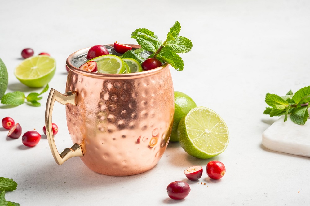 Cranberry Moscow Mule with mint leaves and lime wedges