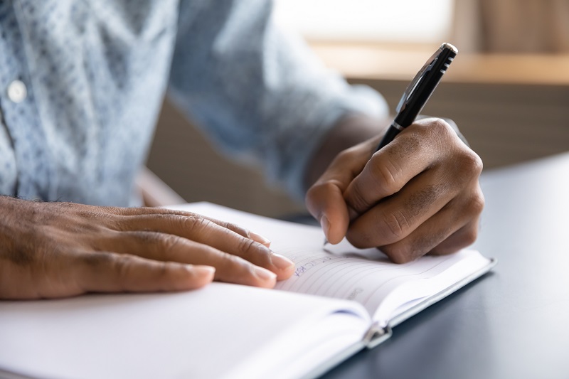 Close up view of man writing in notebook