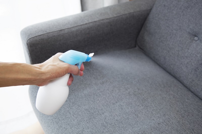 Spraying air freshener in hand on home interior