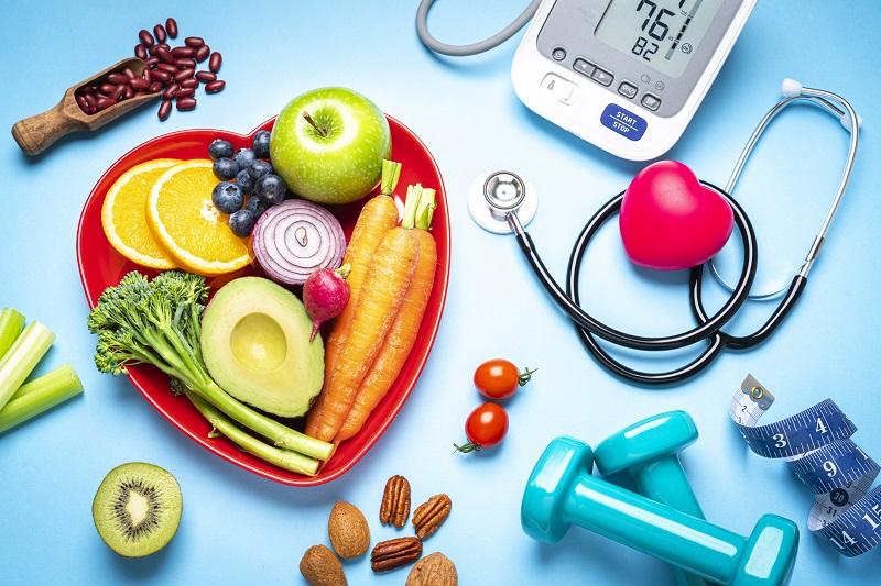 Healthy lifestyle concept with fresh fruits and vegetables. A digital blood pressure monitor, doctor stethoscope, dumbbells and tape measure