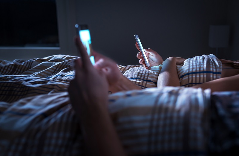 couple at home in bed late at night using mobile phone