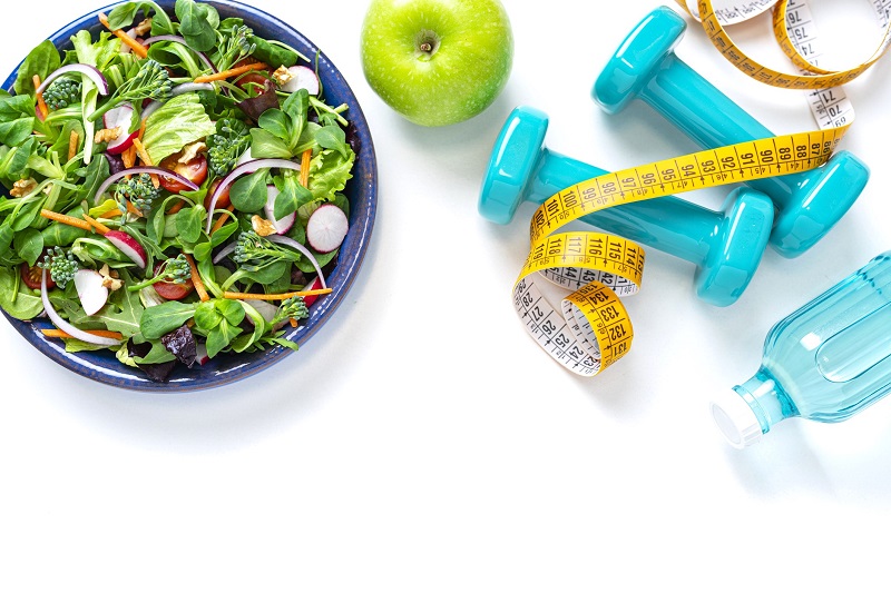 healthy salad, exercise equipment, water bottle and tape measure