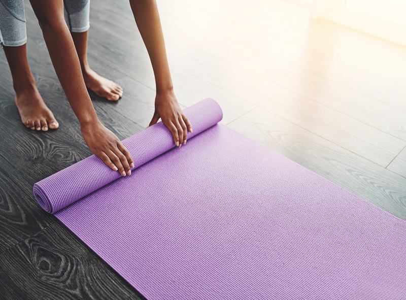 woman rolling up her yoga mat after exercise