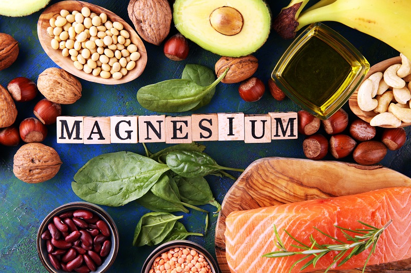 foods containing magnesium: bananas, almonds, avocado, nuts and spinach and eggs on table