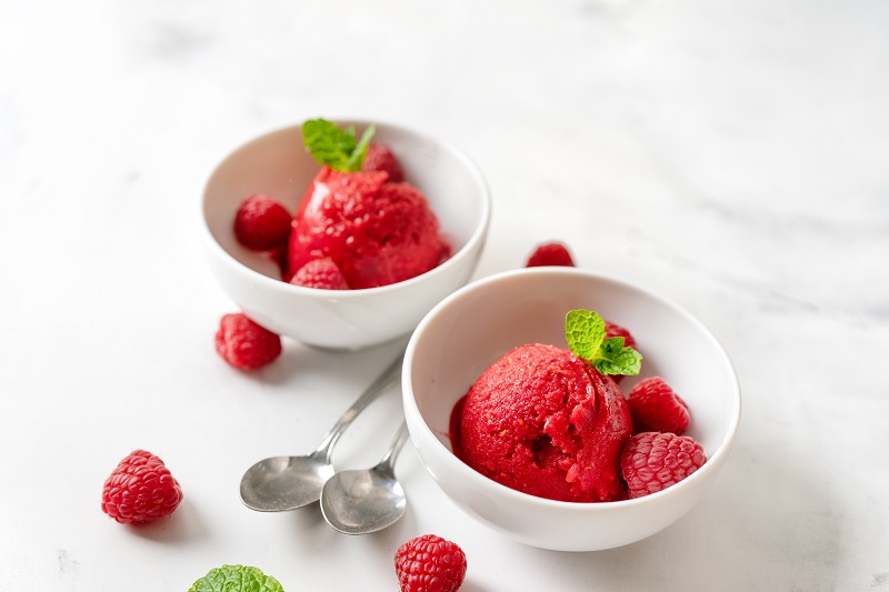 Raspberry sorbet in two cups on white table