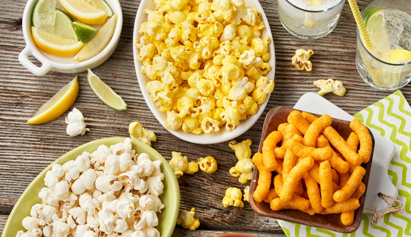 beach snacks popcorn and cheese puffs on a table