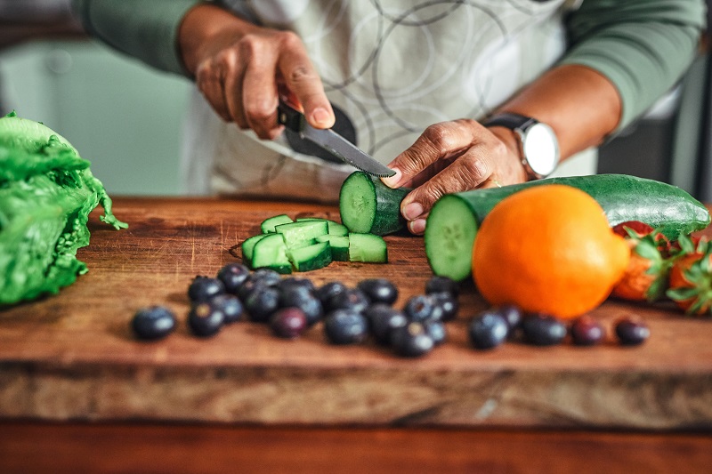 person slicing vegetables on a cutting board