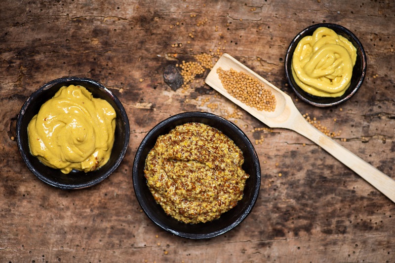 different mustards in bowls for healthy condiments