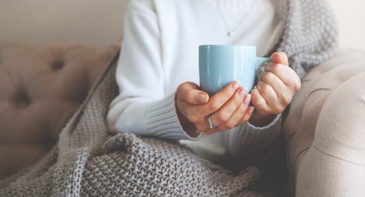 person drinking hot tea in the winter on the couch