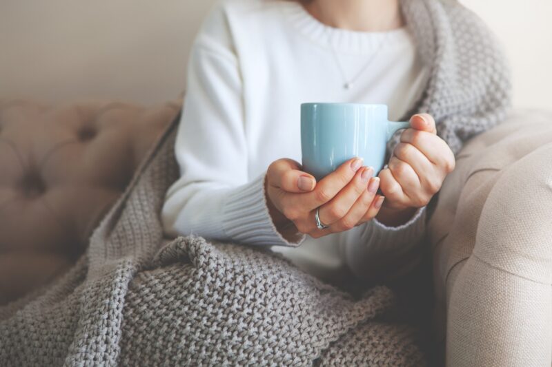 person drinking hot tea in the winter on the couch