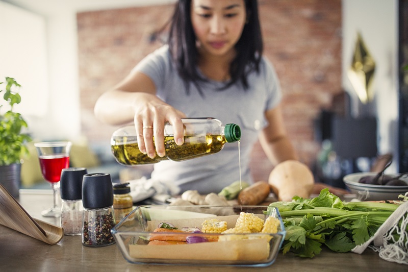 person pouring vegetable oil over a meal