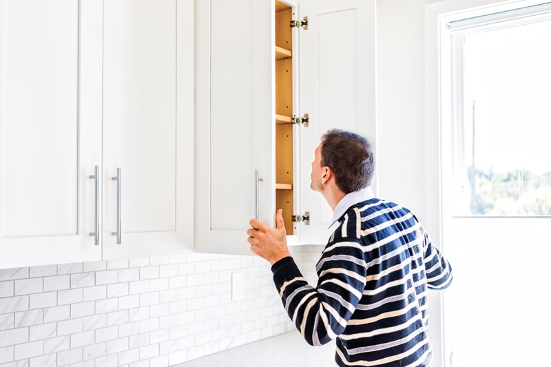 man looking in cabinets