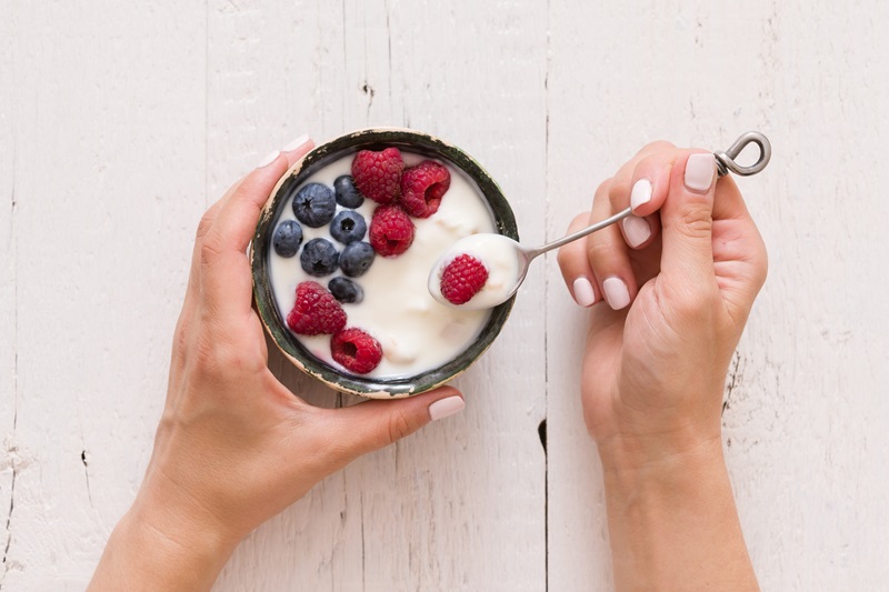person eating soy yogurt with berries