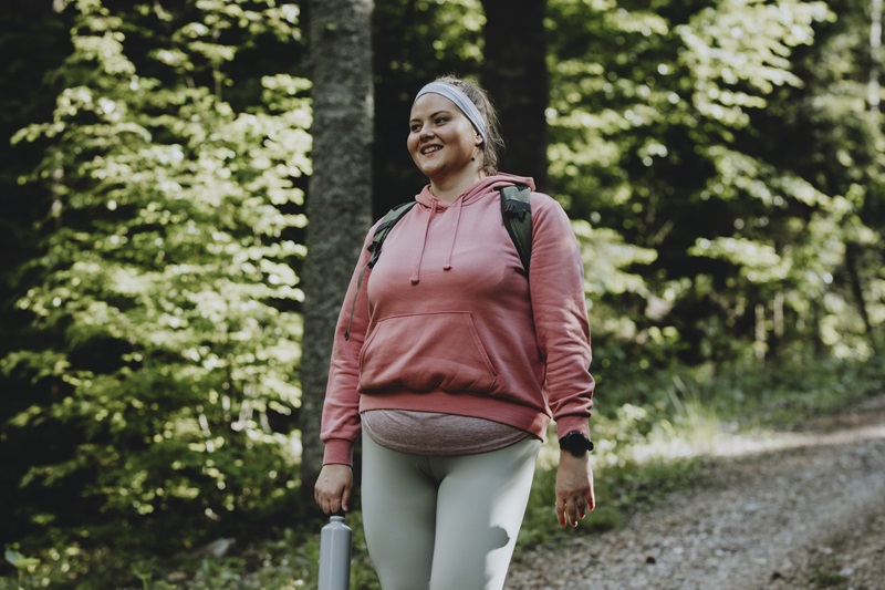 woman walking outside in the woods with a backpack for rucking