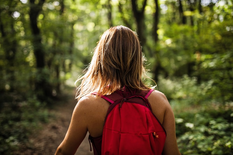 woman walking outside with backpack in the woods