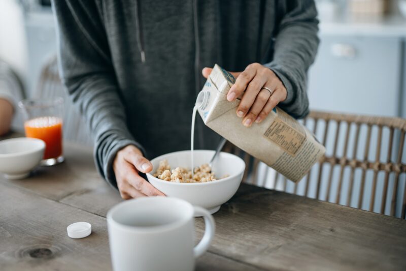 woman pouring milk into a bowl of cereal - ultra-processed foods aren't all unhealthy