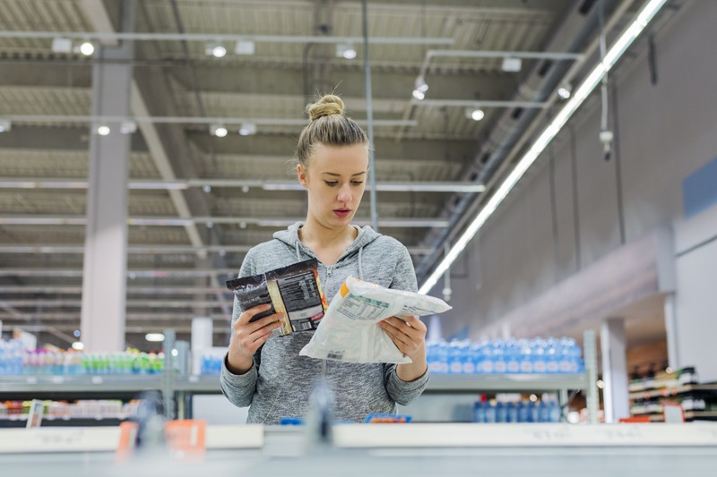 woman reading labels on packages of food in the grocery store