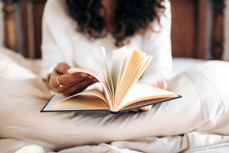 woman reading book before bed instead of phone