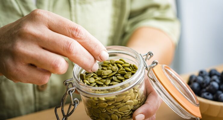 person eating pumpkin seeds, a collagen boosting food rich in zinc