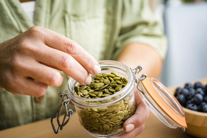 person eating pumpkin seeds, a collagen boosting food rich in zinc