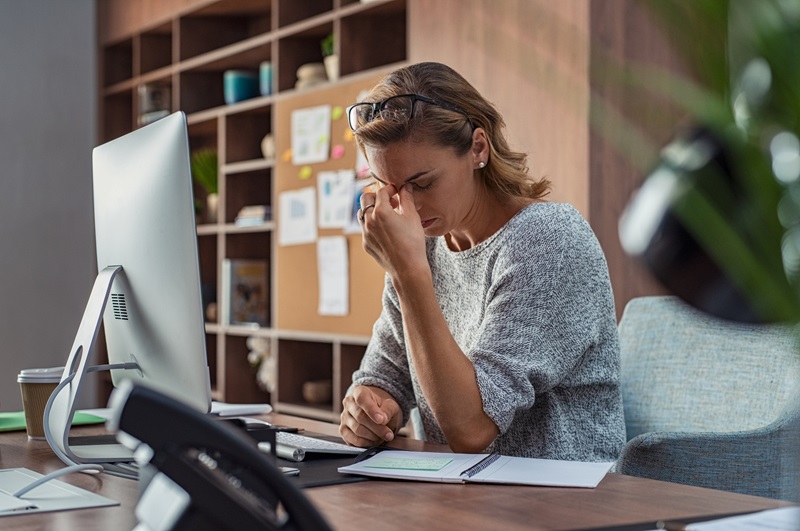 stressed and exhausted woman having a headache in office.