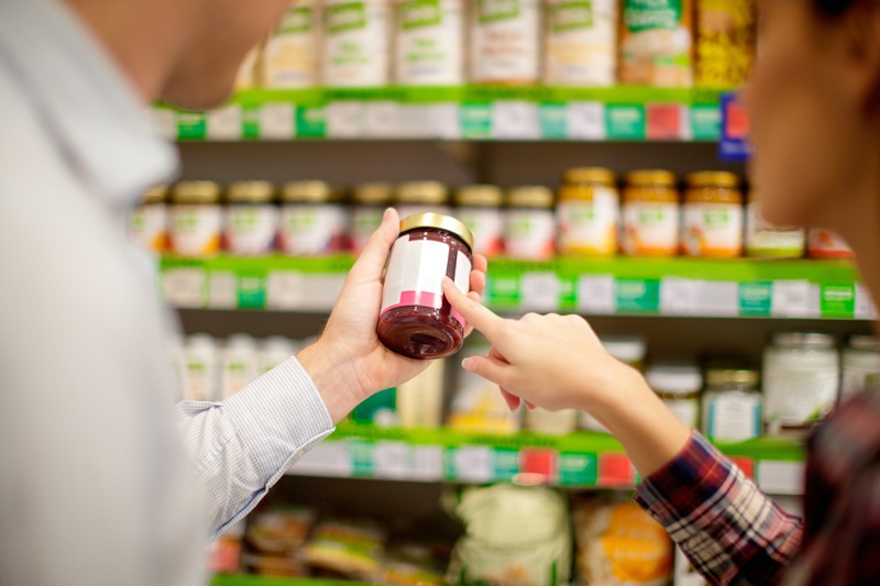 Couple choosing jar of marmalade reading nutrition label