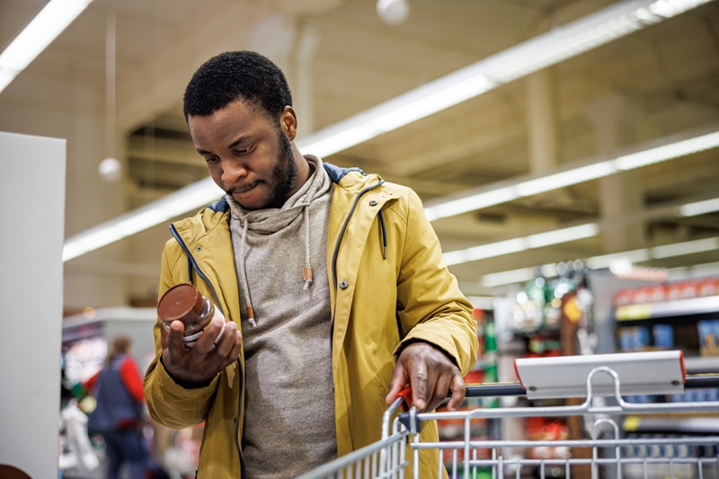 man reads nutrition labels for health claims on product in supermarket