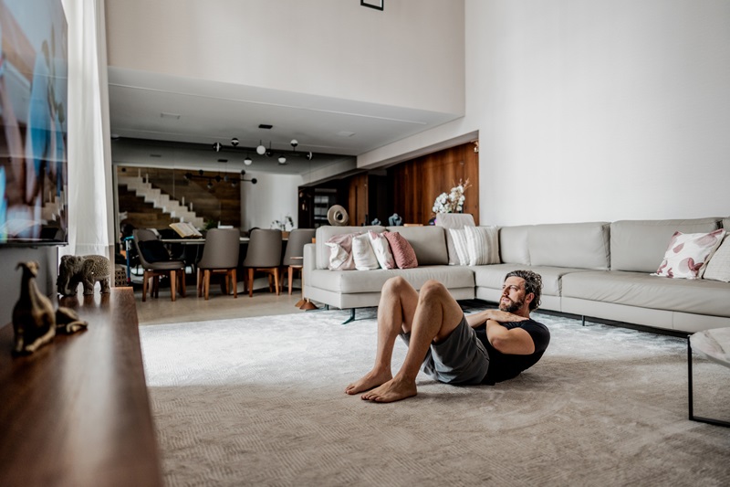 man doing exercise snacks while watching TV in living room