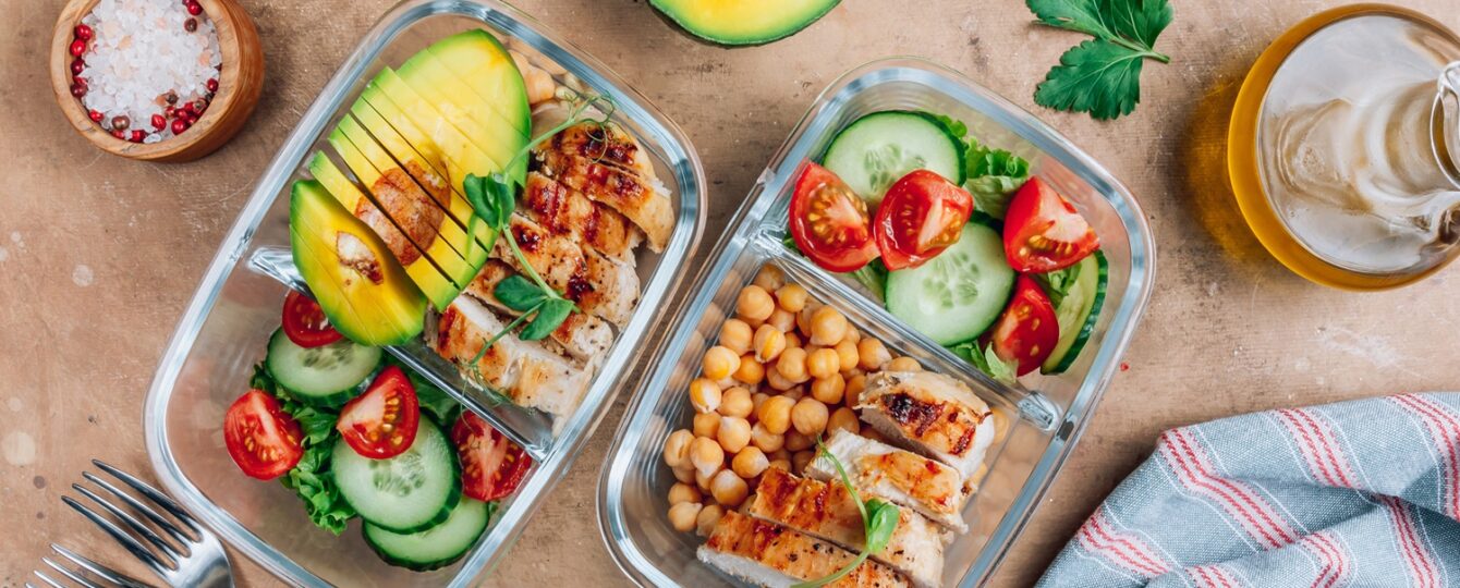 Healthy meal prep containers with chickpeas, chicken, tomatoes, cucumbers and avocados.