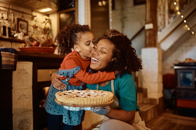 woman hugging young daughter or family member holding a holiday dessert practicing mindfulness