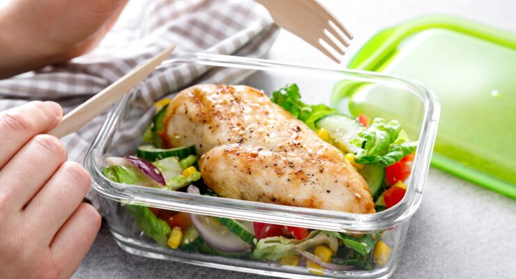 lunch container filled with a high protein meal of chicken breast over a salad