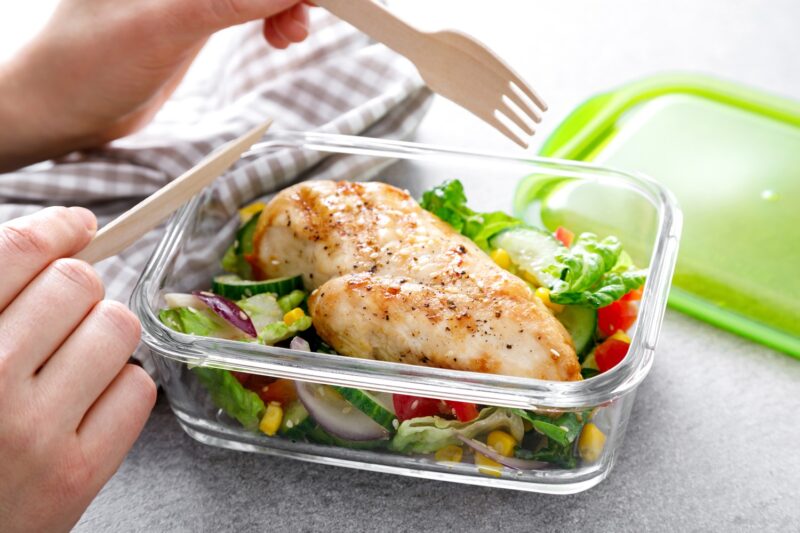 lunch container filled with a high protein meal of chicken breast over a salad