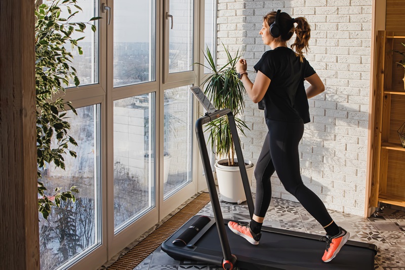 Woman jogging on compact walking pad treadmill in her home gym