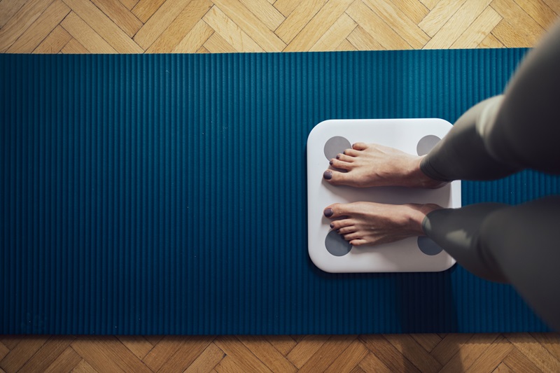 person weighing themselves on a scale