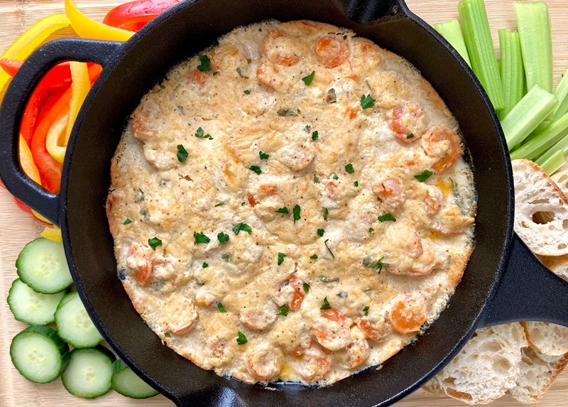 Hot Shrimp Dip surrounded by various dippers like vegetables and sliced bread