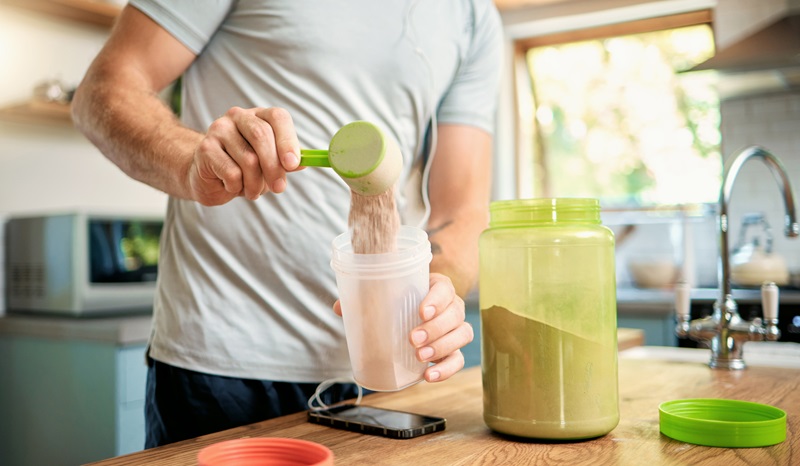 man making a protein shake with protein powder