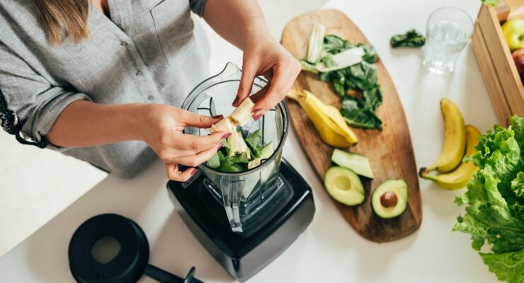 woman preparing a healthy smoothie with fiber rich fruit and avocados with healthy fats to manage hunger hormones