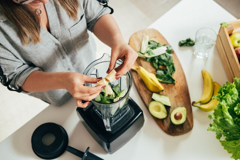 woman preparing a healthy smoothie with fiber rich fruit and avocados with healthy fats to manage hunger hormones